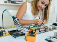 Eine elektrotechnische Assistentin schließt zwei Elektroden an eine Leiterplatte an.