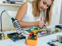 Eine elektrotechnische Assistentin baut auf einer Leiterplatte eine neue Versuchsanordnung auf. 
