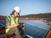 Eine technische Assistentin für regenerative Energietechnik überprüft an ihrem Tablet die richtige Einstellung der Photovoltaik-Anlage.