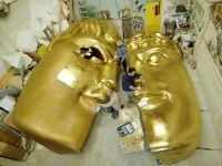 Bühnenplastiker arbeiten an einer riesigen Maske, die aus Kunststoff geschnitzt, mit Fiberglas überzogen und mit Blattgold vergoldet wurde.