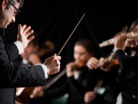 Ein Ensembleleiter dirigiert ein Musikstück während eines Auftritts.