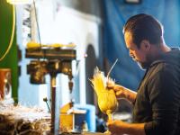 Ein Bürsten- und Pinselmacher fertigt in seiner Werkstatt einen Reisstrohbesen.