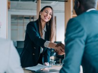 Eine Fremdsprachenkorrespondentin begrüßt zwei ausländische Geschäftspartner.
