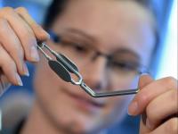 Eine Chirurgiemechanikerin des Medizintechnik-Herstellers Aesculap prüft einen Gefäßclip.