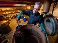 Ein Destillateur stellt Gin nach traditionellen und handwerklichen Methoden mit Wacholderbeeren her.