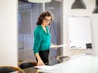 Eine kaufmännische Assistentin / Wirtschaftsassistentin platziert Dokumente auf den Tisch im Besprechungsraum.