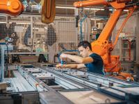 Ein Elektroniker für Automatisierungstechnik installiert neue Roboterarme in einer Fabrik. 
