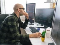 Ein mathematisch-technischer Assistent entwickelt in seinem Büro ein Softwareprogramm am Computer.