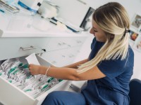 Eine medizinische Dokumentationsassistentin sucht aus einem Hängeregister eine Krankenakte heraus. 