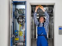 Ein Elektroniker für Informations- und Systemtechnik repariert einen defekten Fahrstuhl.