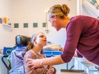 Eine Pflegeassistentin wäscht ein Mädchen, welches in einer Wohngemeinschaft für pflegebedürftige Menschen lebt.