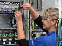 Eine Elektronikerin für Maschinen und Antriebstechnik arbeitet an einer Steuerungseinheit in einem Werk für Kombinationstechnik in Chemnitz.
