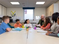 Ein Sozialassistent kümmert sich um eine Gruppe Kinder in der Nachmittagsbetreuung.