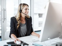 Eine kaufmännische Assistentin/ Wirtschaftsassistentin für Informationsverarbeitung führt ein Telefongespräch mit einem Kunden.