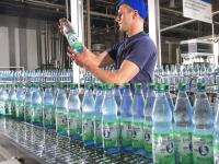 Eine Fachkraft für Lebensmitteltechnik prüft eine Mineralwasserflasche an einer Abfüllanlage in Bad Liebenwerda.