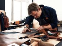 Eine Fachkraft für Lederverarbeitung vermisst in der Werkstatt Leder für die Herstellung von Rucksäcken.
