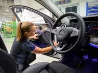 Eine Fahrzeuginterieur-Mechanikerin montiert eine Türinnenverkleidung in eine Autotür.