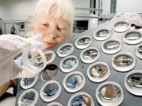 Eine Feinoptikerin prüft Linsen im Werk der Carl Zeiss Jena GmbH.