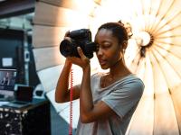 Eine Fotografin fotografiert vor einem Reflektorschirm in ihrem Fotostudio.