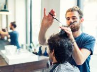 Ein Friseur schneidet im Salon einem Kunden die Haare.