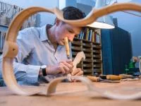 Ein Geigenbauer schnitzt in seiner Werkstatt am Schneckenkopf für den Nachbau einer historischen Geige.