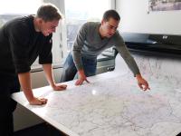 Zwei Geomatiker vom Landesbetrieb Straßenbau Nordrhein-Westfalen überprüfen eine Landkarte, die sie erstellt haben.