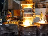 Ein Gießereimechaniker gießt hoch erhitztes Metall in eine Form für ein Werkstück.