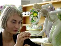 Eine Glas- und Porzellanmalerin retuschiert in der Restaurierwerkstatt der Staatlichen Porzellan-Manufaktur Meissen eine neue Hand an der Figur "Die Kugelspielerin". 