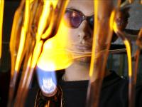 Ein Glasapparatebauer erhitzt einen Glaskolben, um ihn formbar zu machen.