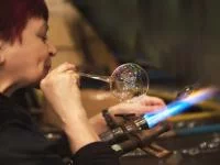 Eine Glasbläserin formt Christbaumschmuck aus erhitztem Glas.
