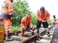 Mehrere Gleisbauer verbinden beim Bahnhof Eyach eine neue Weiche mit den Gleisen.