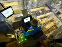 Ein Holzbearbeitungsmechaniker verarbeitet im Sägewerk mit einer automatischen Säge einen Baumstamm zu Brettern.