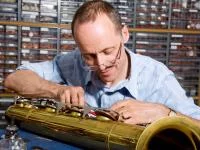 Ein Holzblasinstrumentenmacher arbeitet an einem Baritonsaxophon.
