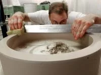 Ein Mitarbeiter der Porzellanfabrik Hermsdorf prüft und korrigiert die Oberfläche eines Werkstücks aus Rohware, das für eine Porzellanmühle zum Mahlen von Hartstoffen bestimmt ist.