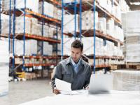 Ein Kaufmann für Spedition und Logistikdienstleistung überprüft die Lieferpapiere einer Warenlieferung.