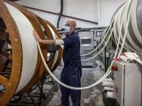 Ein Kerzenhersteller arbeitet an den Trommeln einer Kerzenzuganlage.