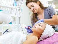 Eine Kosmetikerin behandelt das Gesicht ihrer Kundin mit einem Mesotherapiegerät.