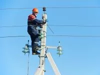Ein Elektroanlagenmonteur arbeitet in luftiger Höhe am Strommast.