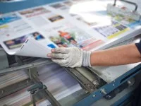 Ein Medientechnologe Druckverarbeitung bedient eine Kalandermaschine zur Beschichtung.
