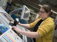 Eine Medientechnologin Druck prüft die Druckqualität mit einem Spektralphotometer.