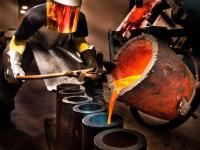 Ein Metall- und Glockengießer gießt den geschmolzenen Stahl in die Werkstückformen.