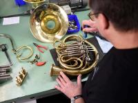 Ein Metallblasinstrumentenmacher baut in seiner Werkstatt ein Horn.