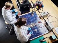 Zwei Physiklaboranten arbeiten an einem 3D-gedrucktem Turbinenrad und an einem Solarpanel.