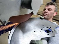 Ein Präzisionswerkzeugmechaniker der Firma Astor Schneidwerkzeuge GmbH schleift ein Industriemesser aus rostbeständigem Spezialstahl.