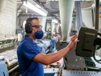 Ein Produktionsmechaniker - Textil bedient eine Textilmaschine.