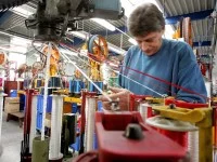 Ein Seiler spannt im Tauwerk Liros Schnüre in eine Maschine.