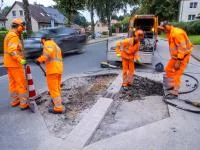 Straßenwärter brechen bei der Schadstellensanierung an einer Bushaltestelle den alten Fahrbahnbelag auf und bereiten die Erneuerung der Fahrbahn vor.