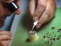 Ein Uhrmacher arbeitet mit einer Pinzette an einer mechanischen Armbanduhr. 