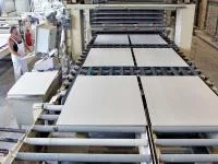 Ein Verfahrensmechaniker in der Steine- und Erdenindustrie überwacht die Produktion von Gipsfaserplatten.