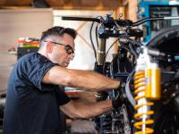 Ein Zweiradmechatroniker repariert in der Werkstatt ein Motorrad.